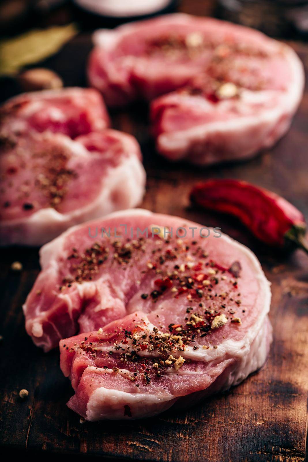 Pork loin steaks with ground spices on cutting board by Seva_blsv