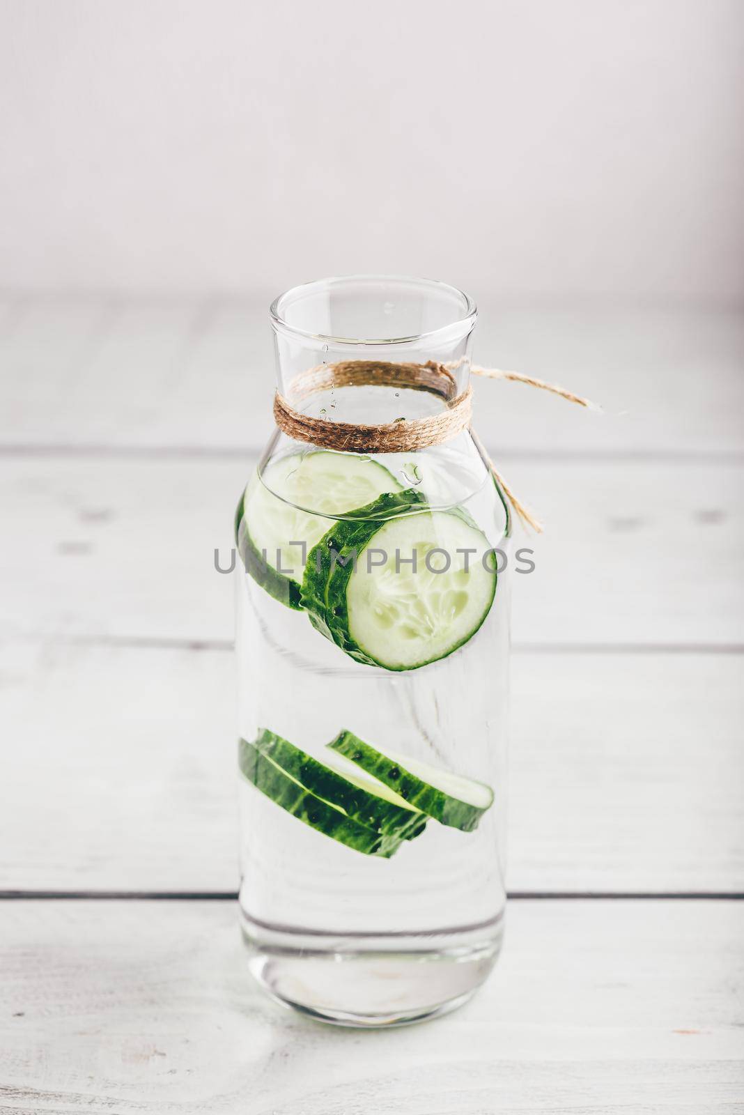 Infused water with sliced cucumber in glass bottle