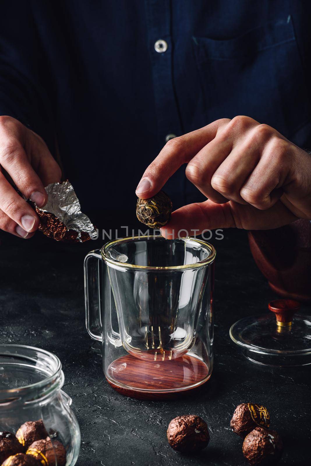 Steeping tea. Putting tea leaves into glass mug