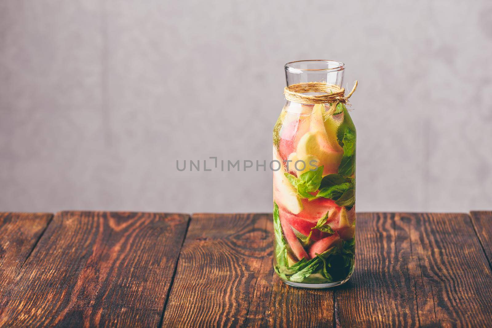 Bottle of Infused Water with Sliced Peach and Basil Leaves.