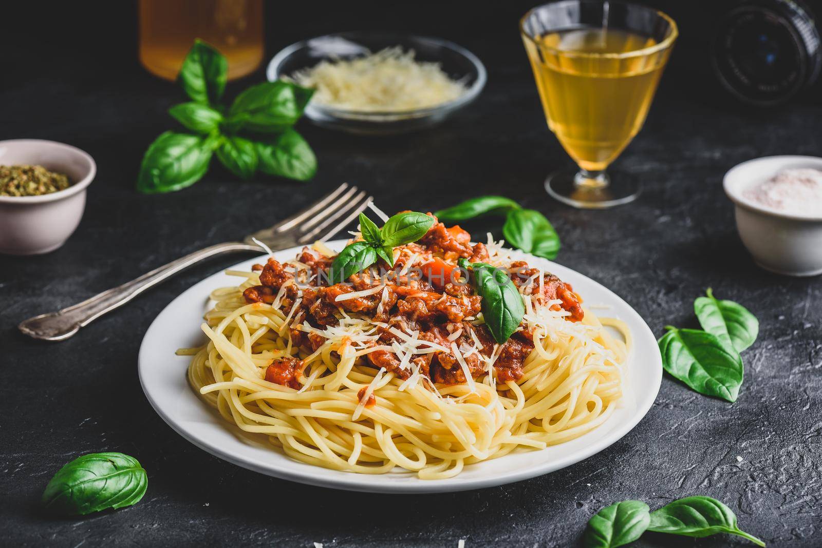 Spaghetti with bolognese sauce, grated parmesan cheese and fresh basil leaves