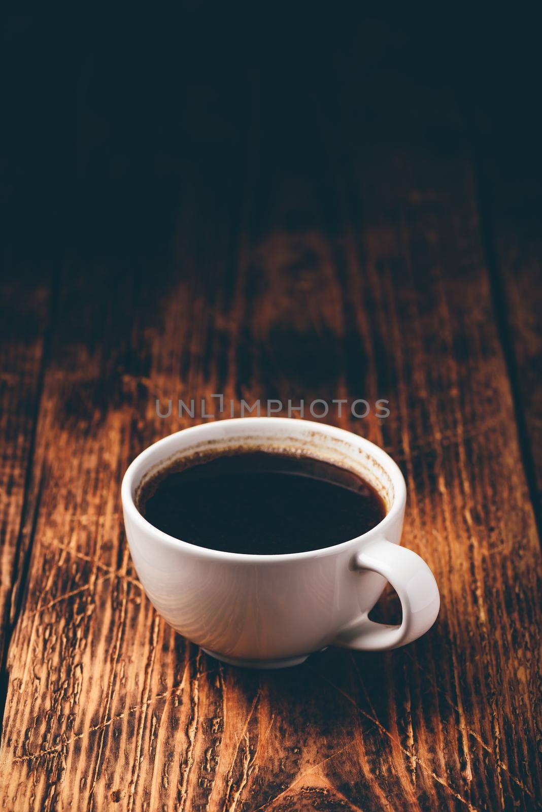 Black coffee in white cup over wooden surface