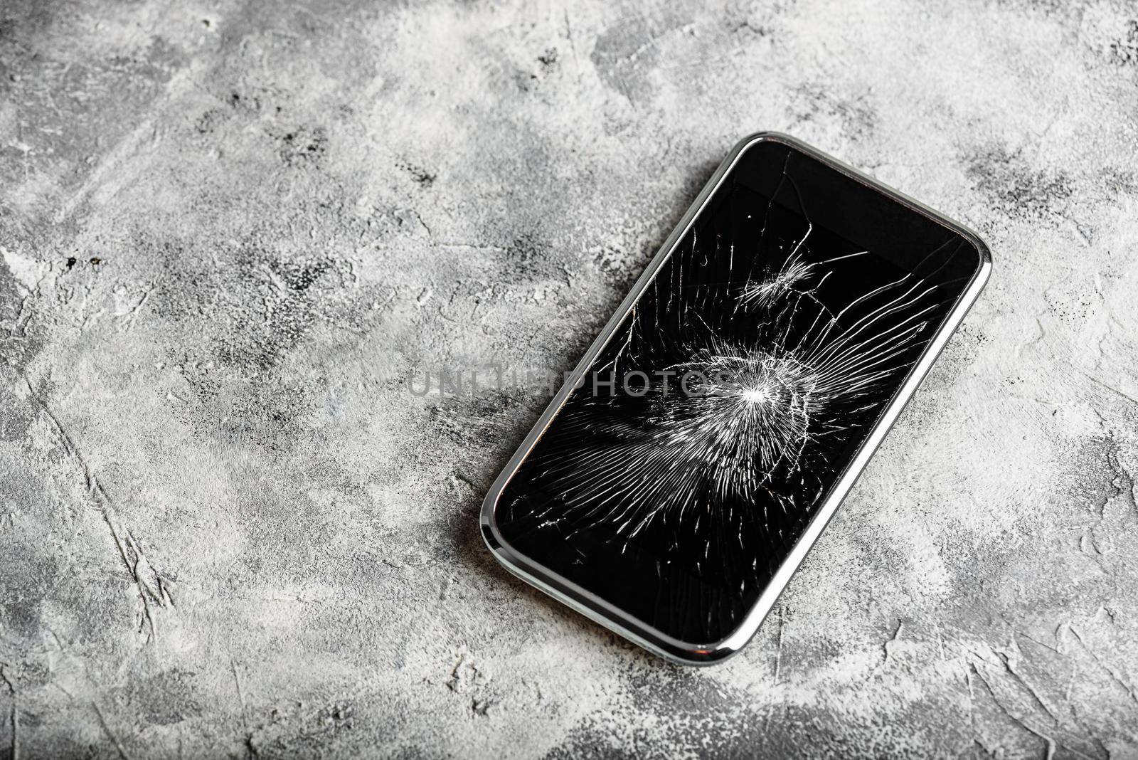 Smartphone with cracked screen over concrete background