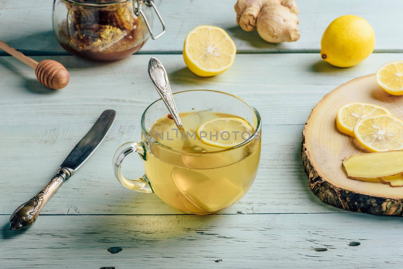 Cup of tea with lemon, honey and ginger over wooden surface