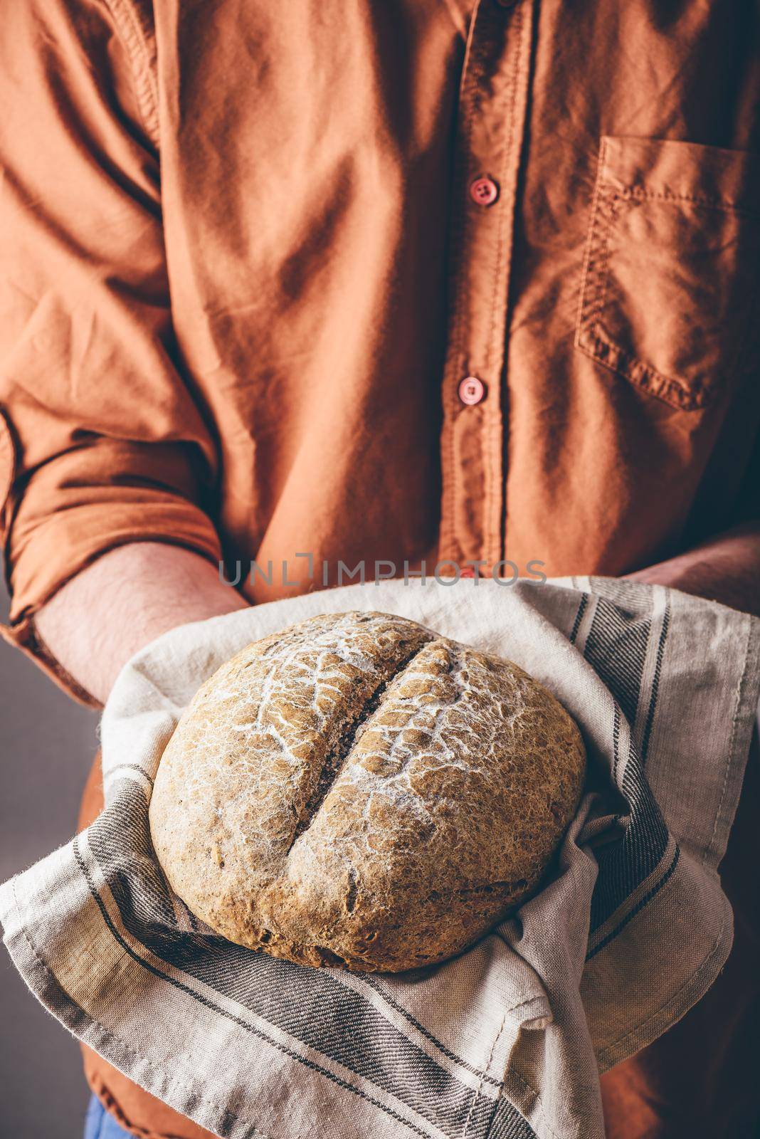 Man holds a loaf of freshly baked rye bread