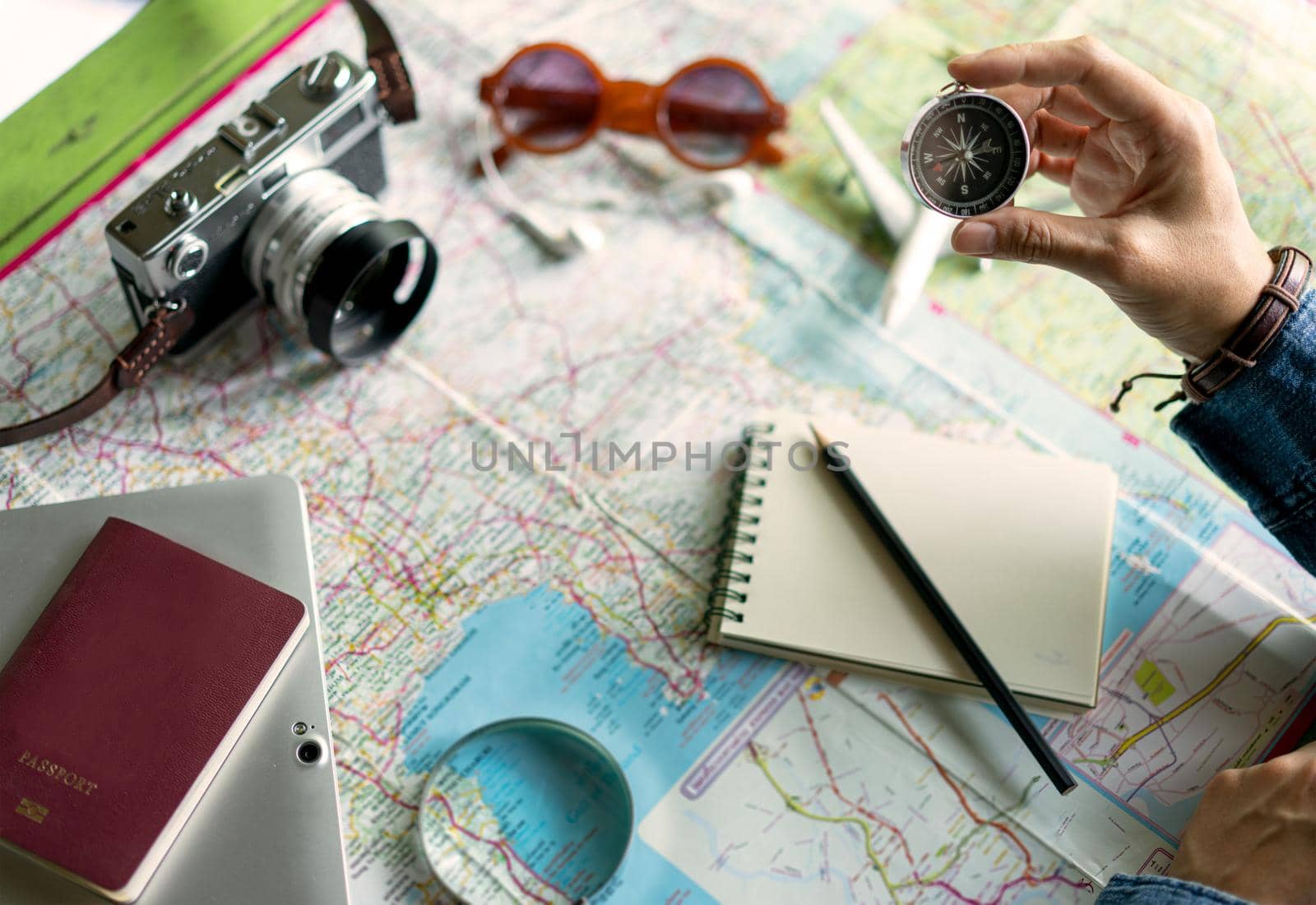 Hand holding compass for planning vacation trip and accessories for travel