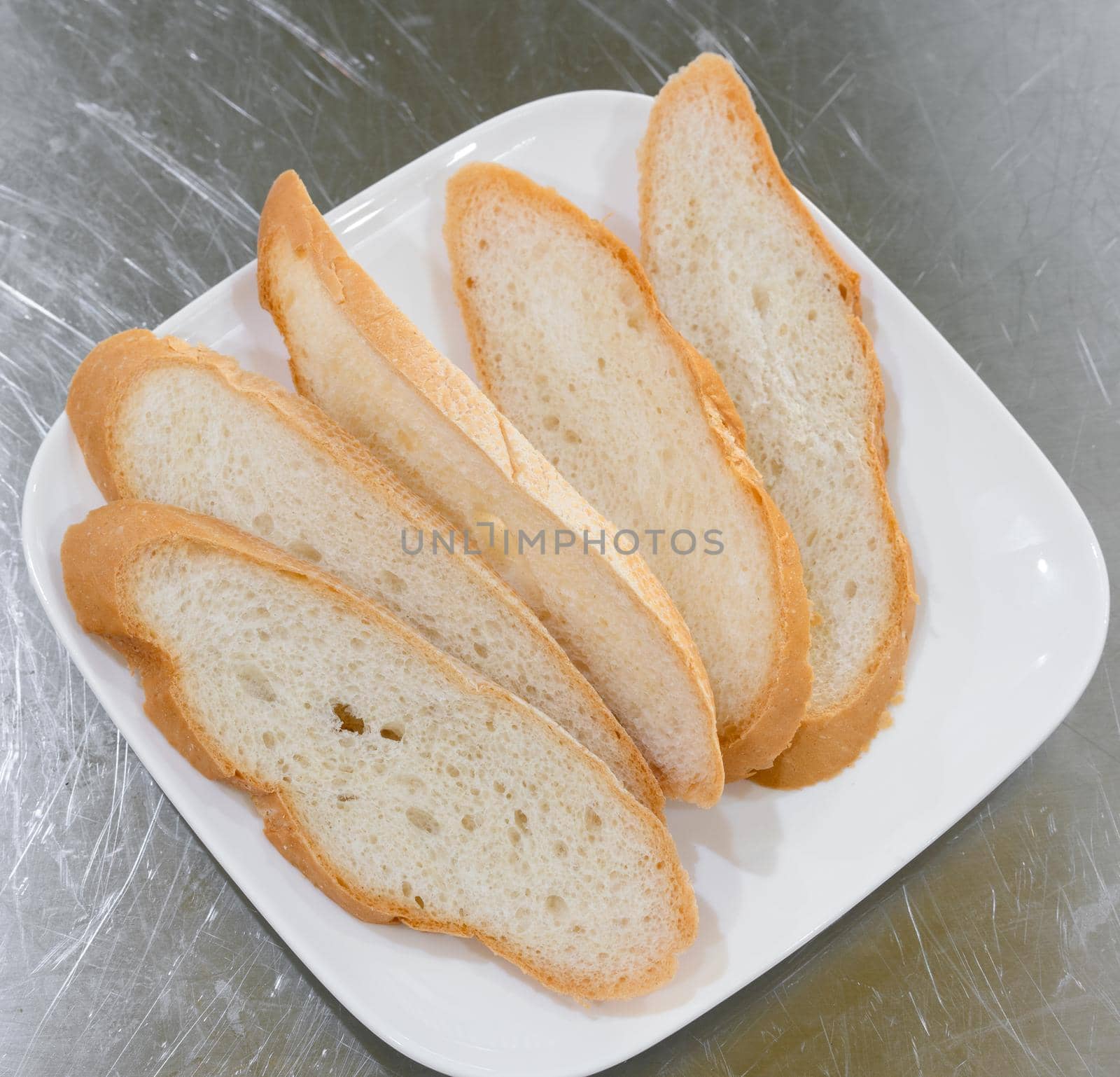 Bread sliced in plate on stainless table by Buttus_casso