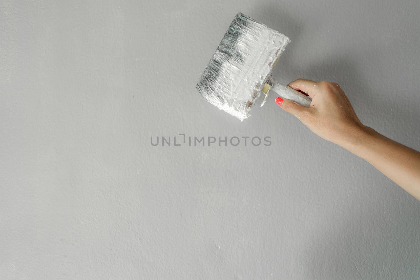 Hand holding paint brush on wall for painting by Buttus_casso