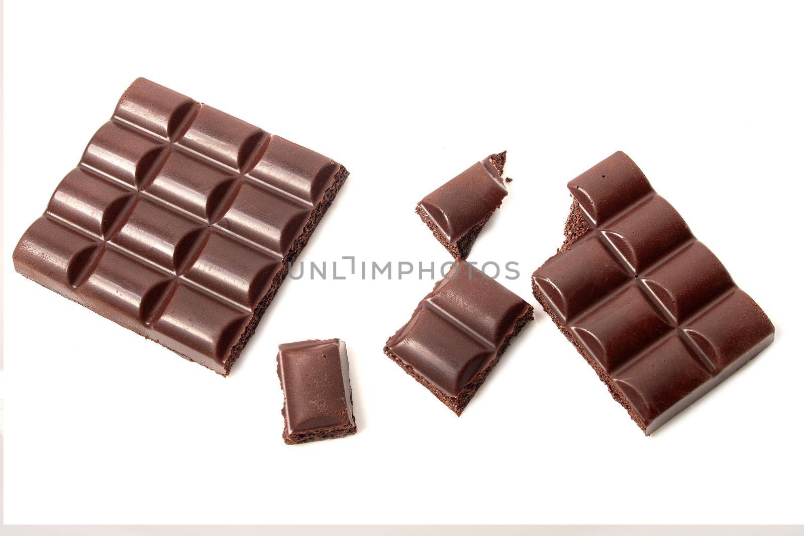 Broken bar of dark porous chocolate, pieces of chocolate on white isolated background