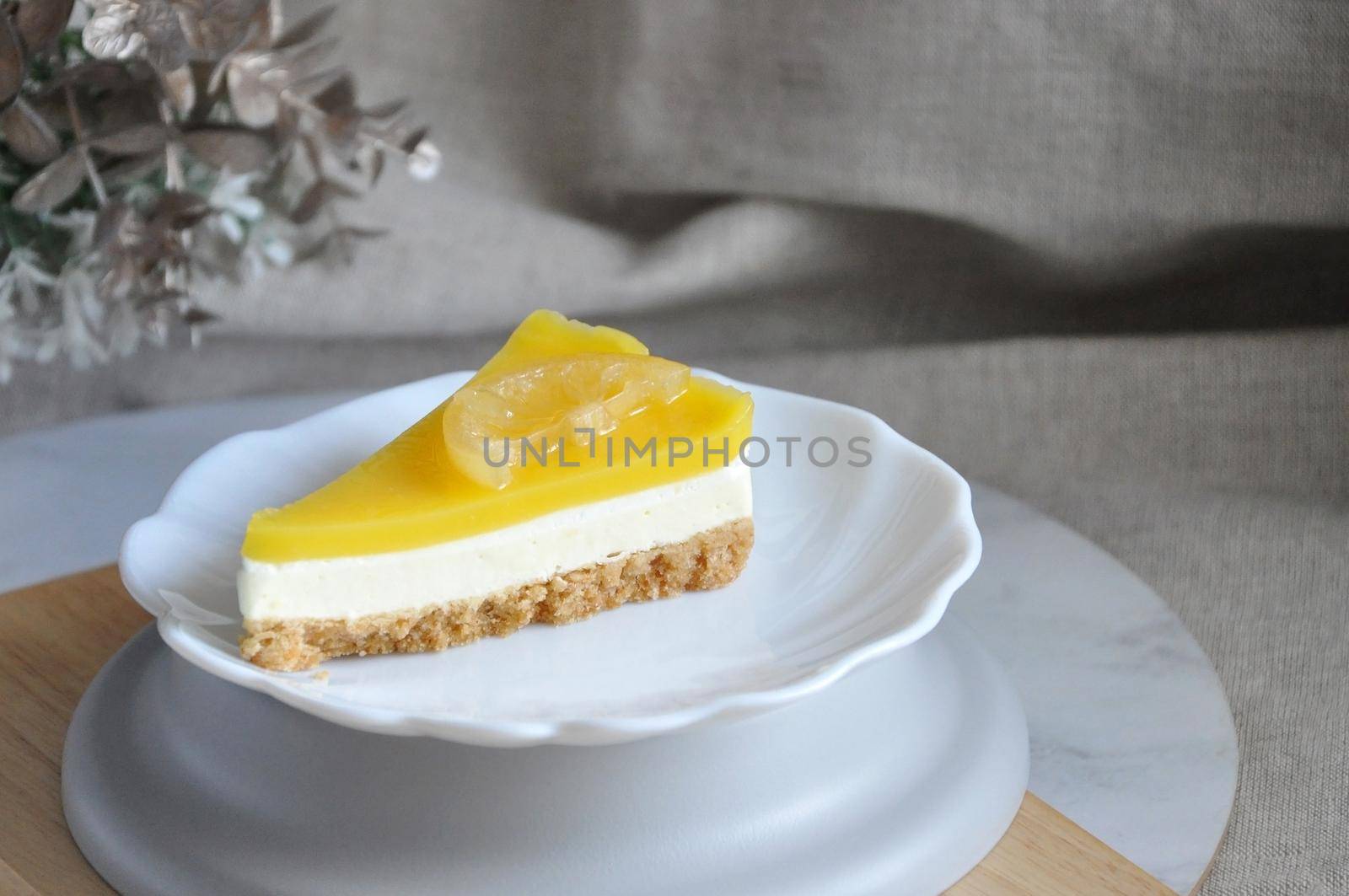 A slice of lemon cheese tart on white dish with copy space on neutral color background