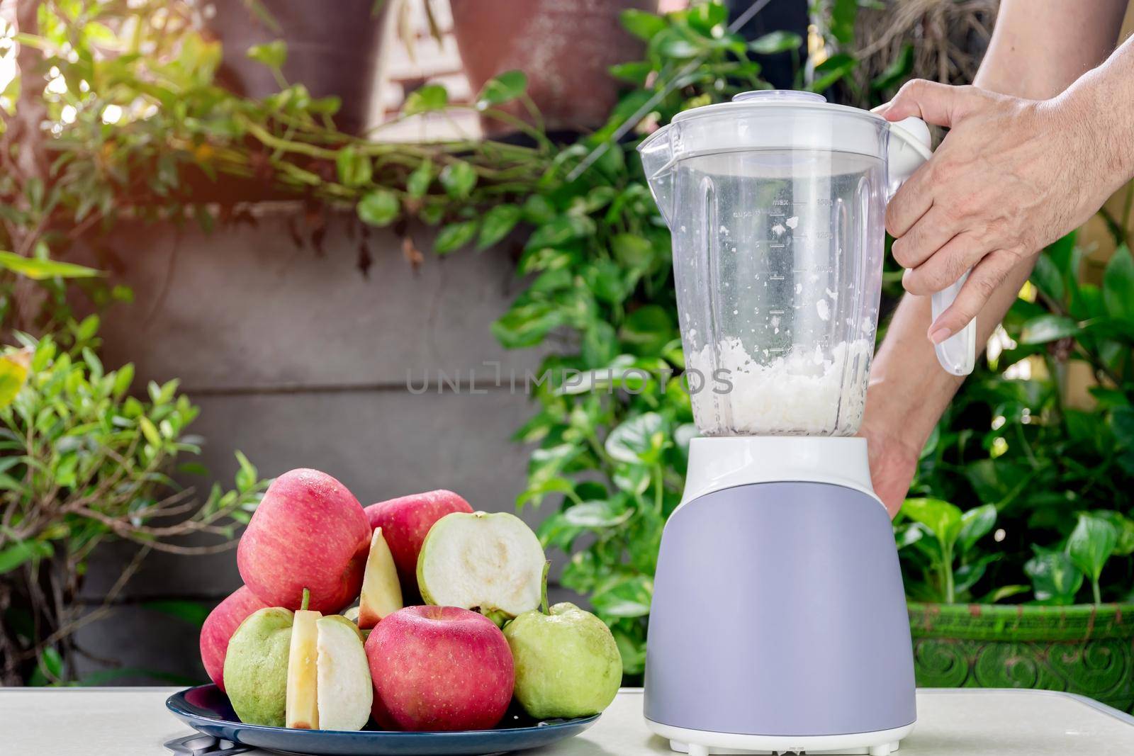 Hand of people are using an electric blender to making fresh apple and guava juice. by wattanaphob