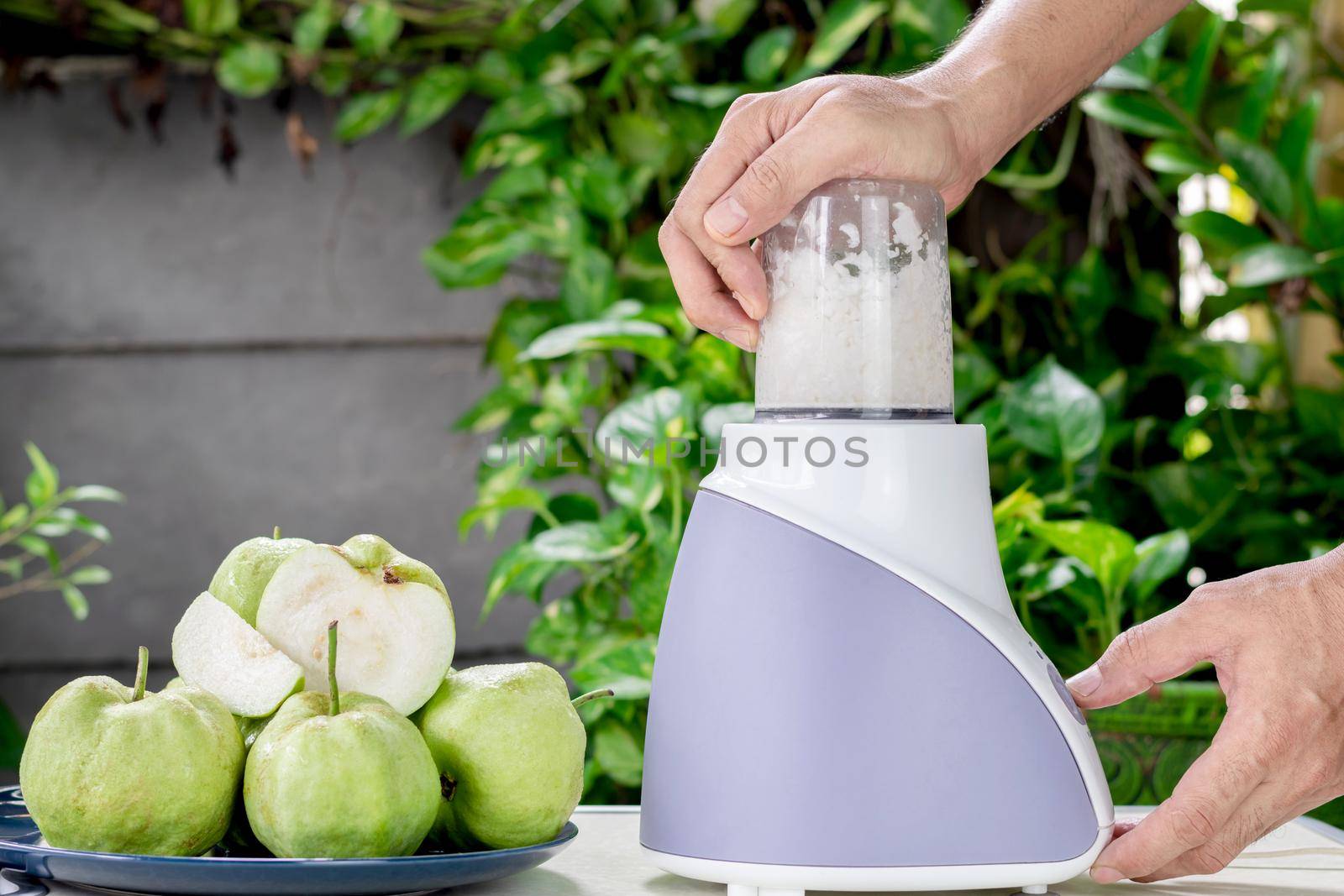 Hand of people are using an electric blender to making fresh guava juice.