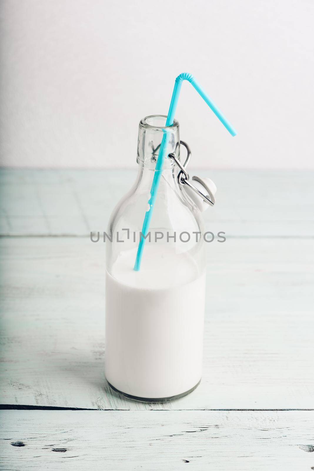 Milk in glass bottle with blue straw