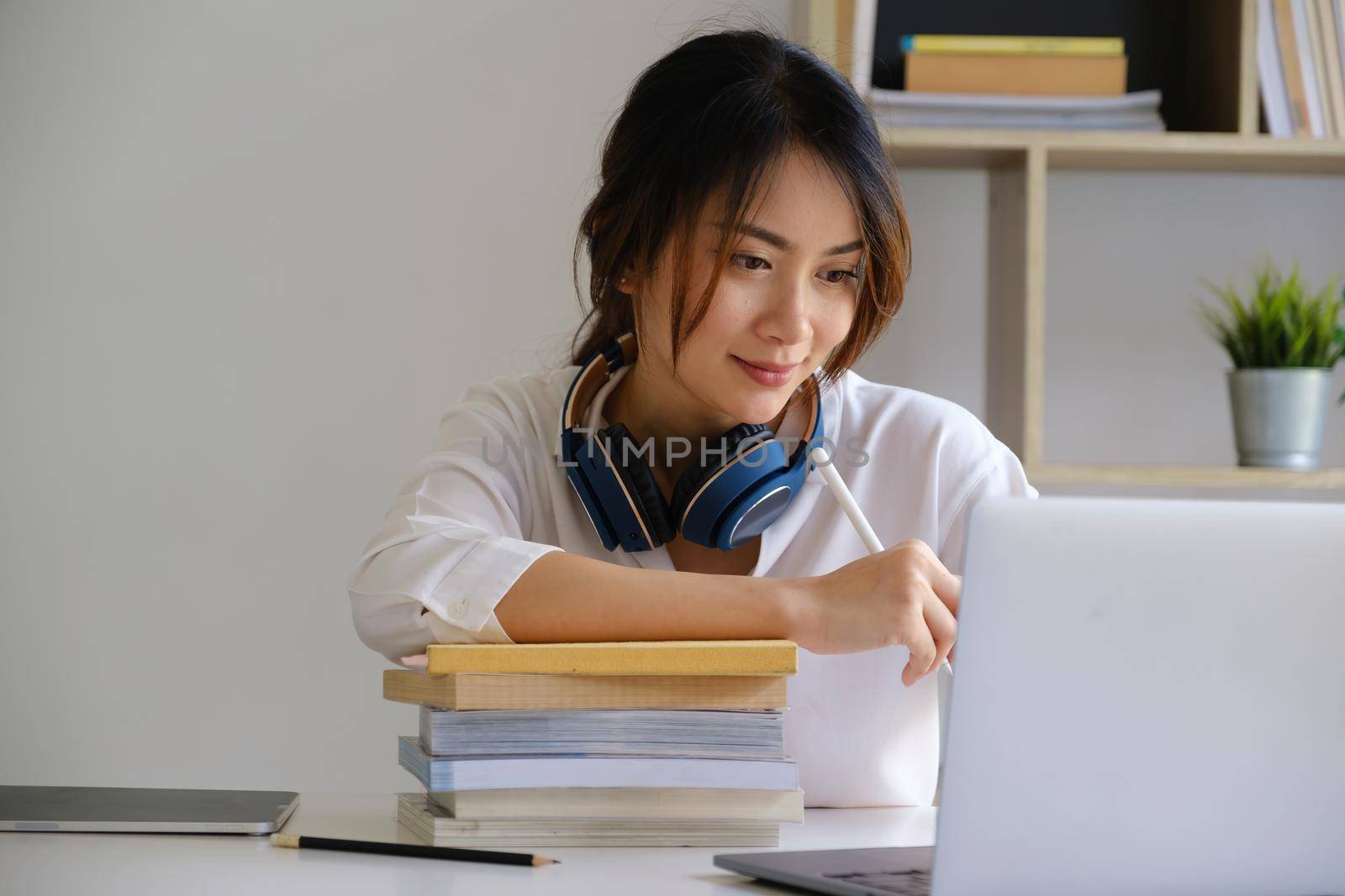 Cheerful young asian woman using laptop computer at home. Student female in living room. online learning, studying , online shopping, freelance, asean concept.