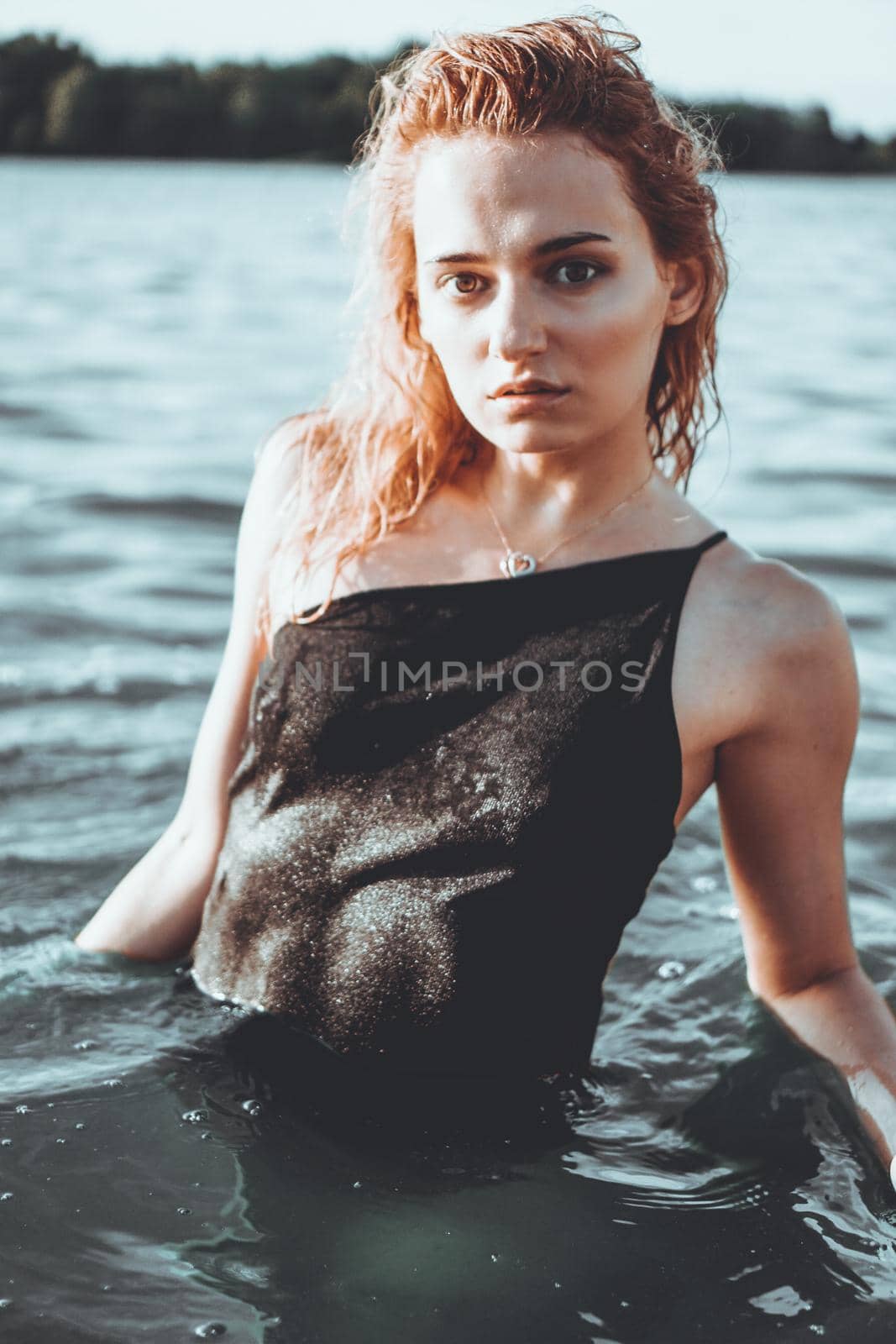 Young beautiful woman standing in the water. Black swimsuit. Vintage style. vertical photo