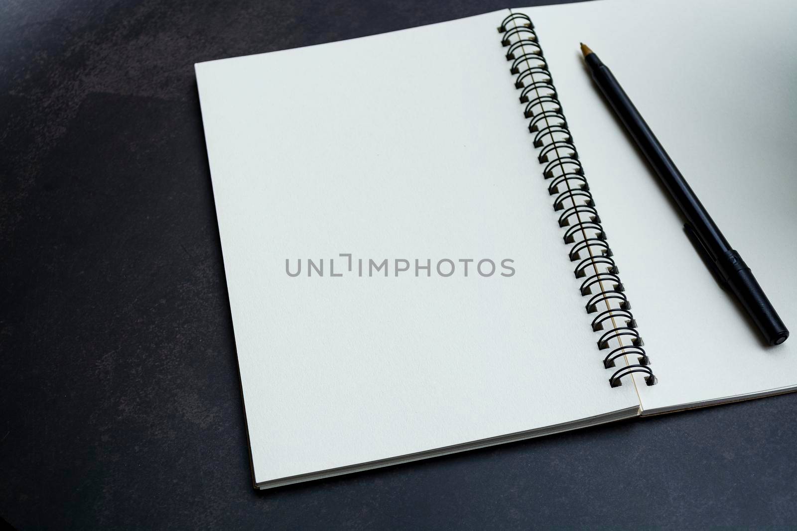 White notebook and pen on dark background. Space for text