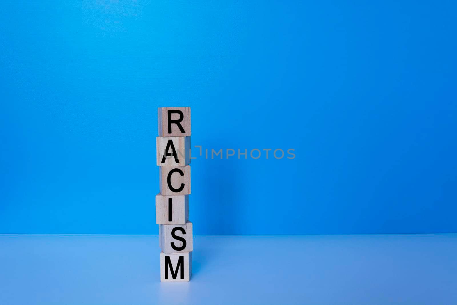 Racism text on wooden block with blue background