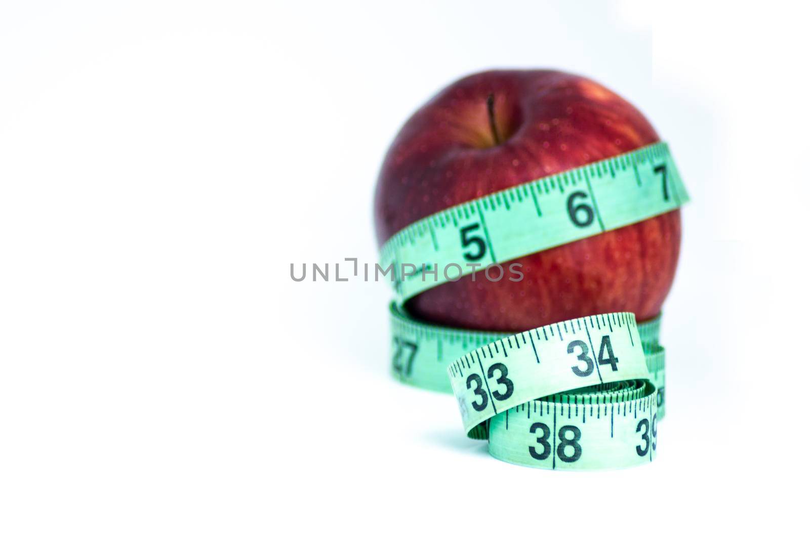 Blurred red apple with measuring tape isolated on white - Diet concept