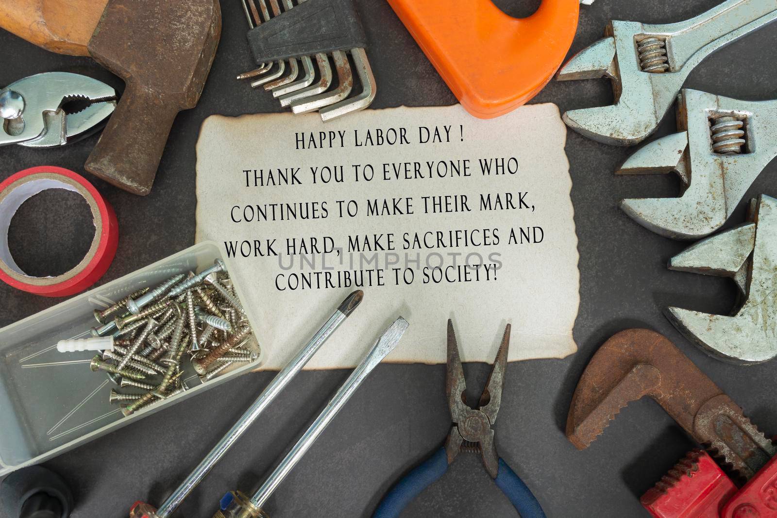 Text on burned edge paper with repair equipment and many handy tools on a dark background. Labor day concept