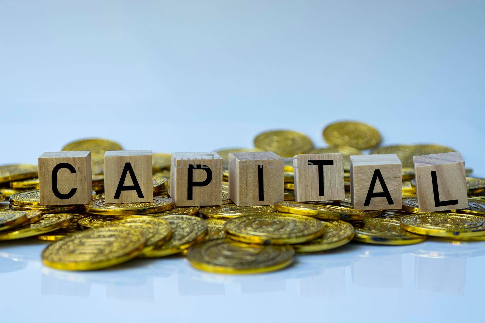 Capital text on wood block with a pile of gold coins