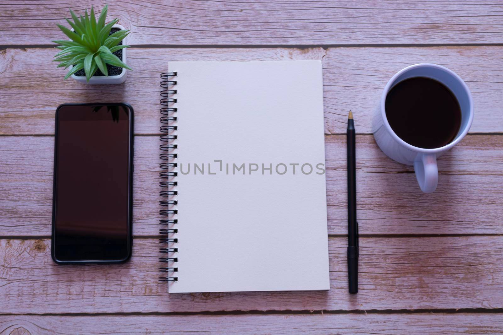 Home office workspace with notepad, pen, coffee and potted plant. Flat lay and top view. Space for text