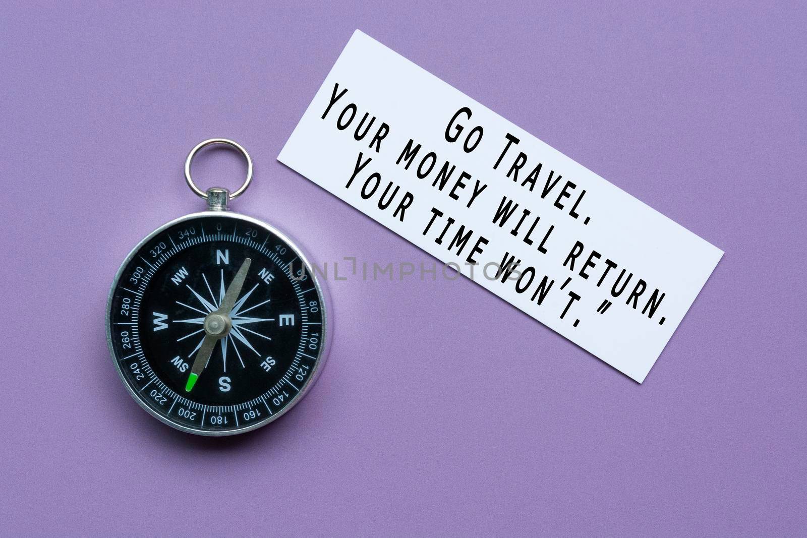 Text on white paper with classic round compass on purple background - Motivational quote about journey