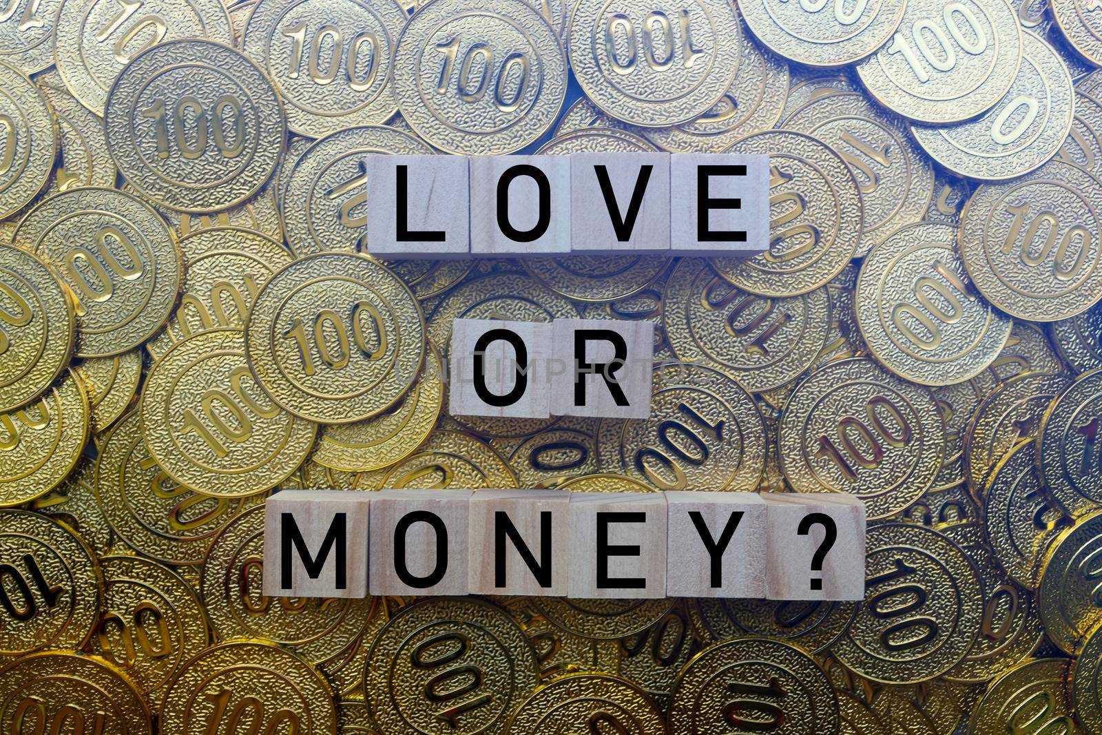 Love or money text on wood block with a pile of gold coins