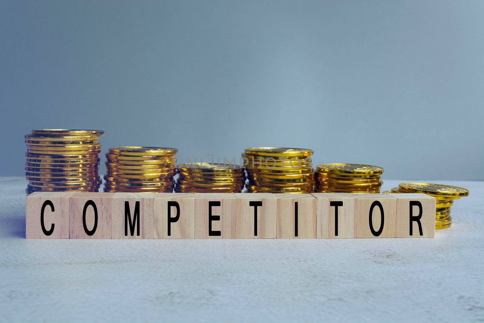 Competitor text on wood block with a pile of gold coins