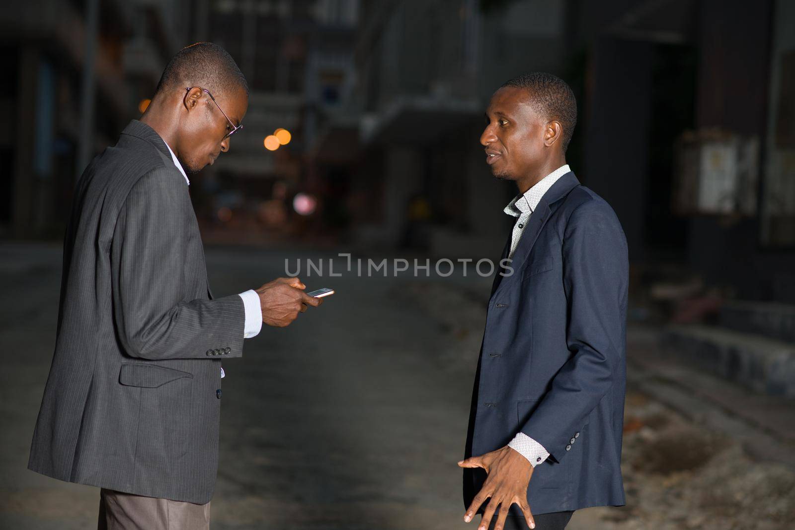 Small group of business people talking outdoors using mobile phone after work