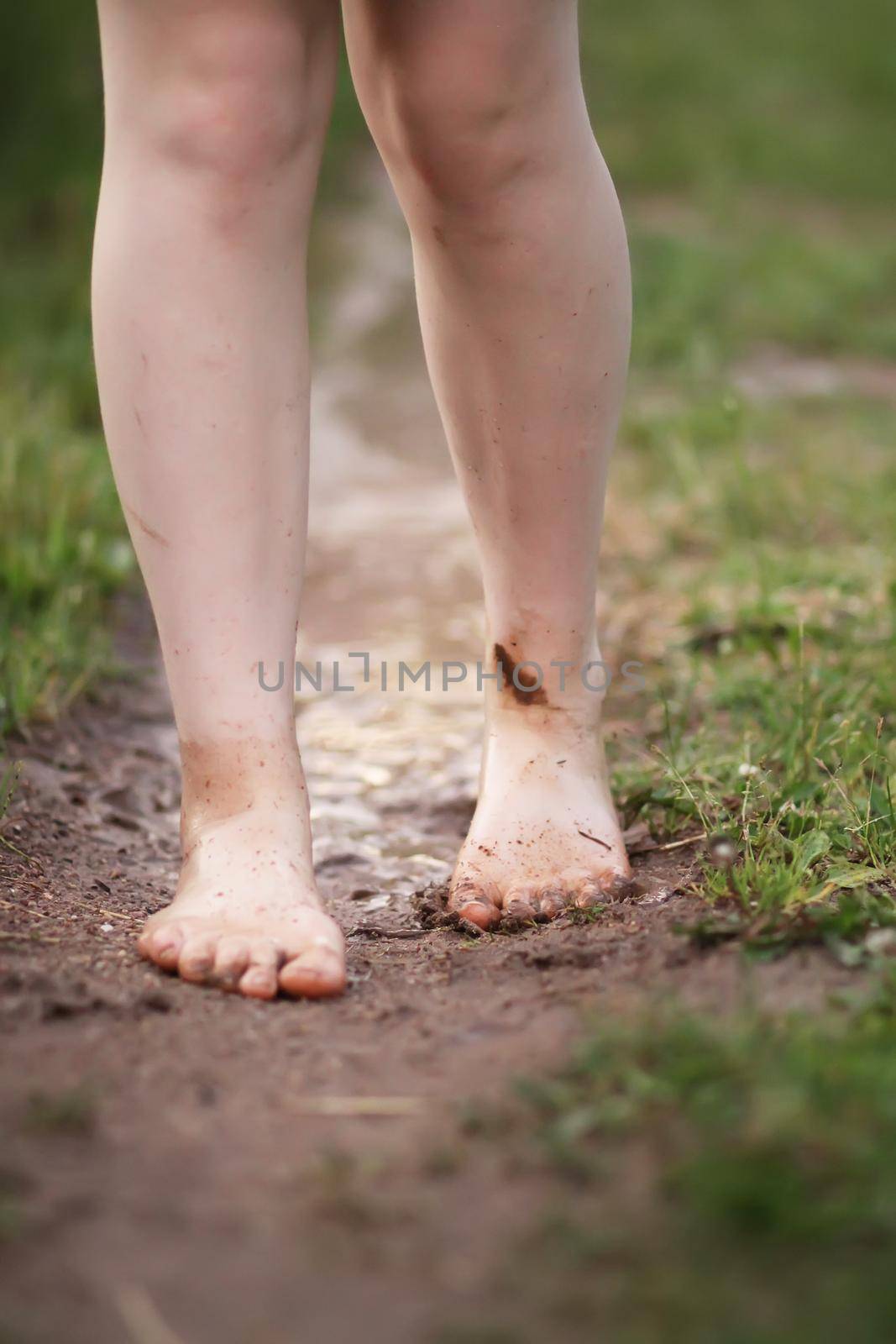 Barefoot girl walks through a puddles of water after the summer rain. by nightlyviolet