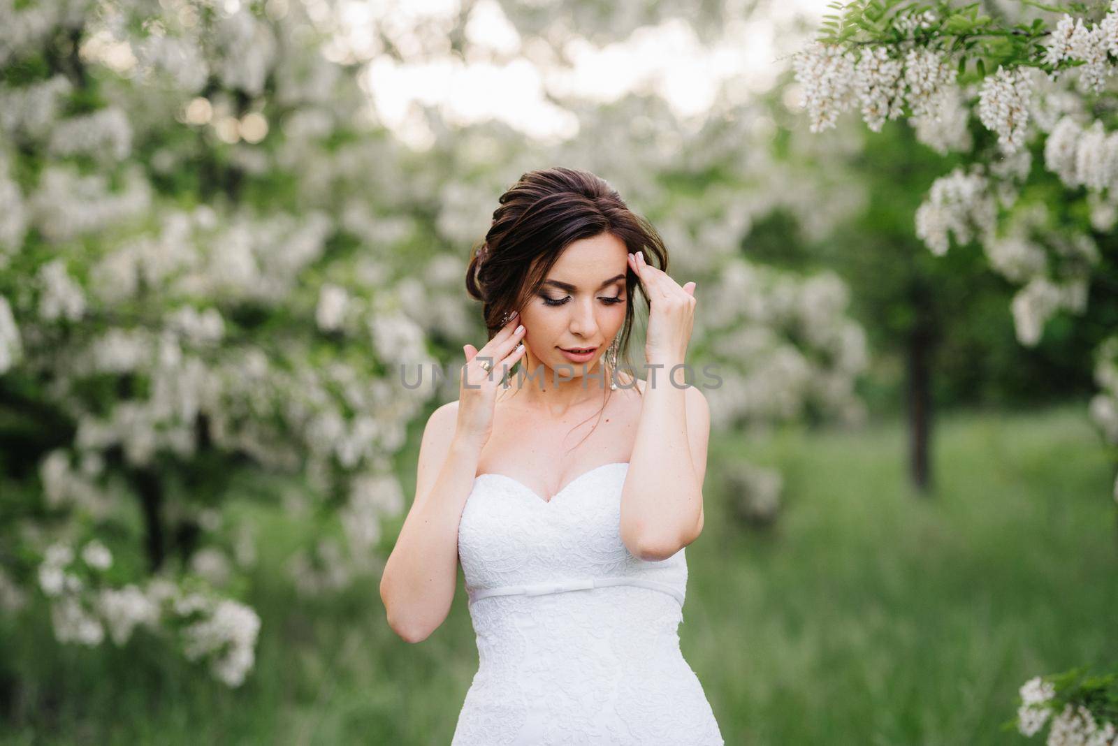 bride in a white dress with a large spring bouquet in a green forest