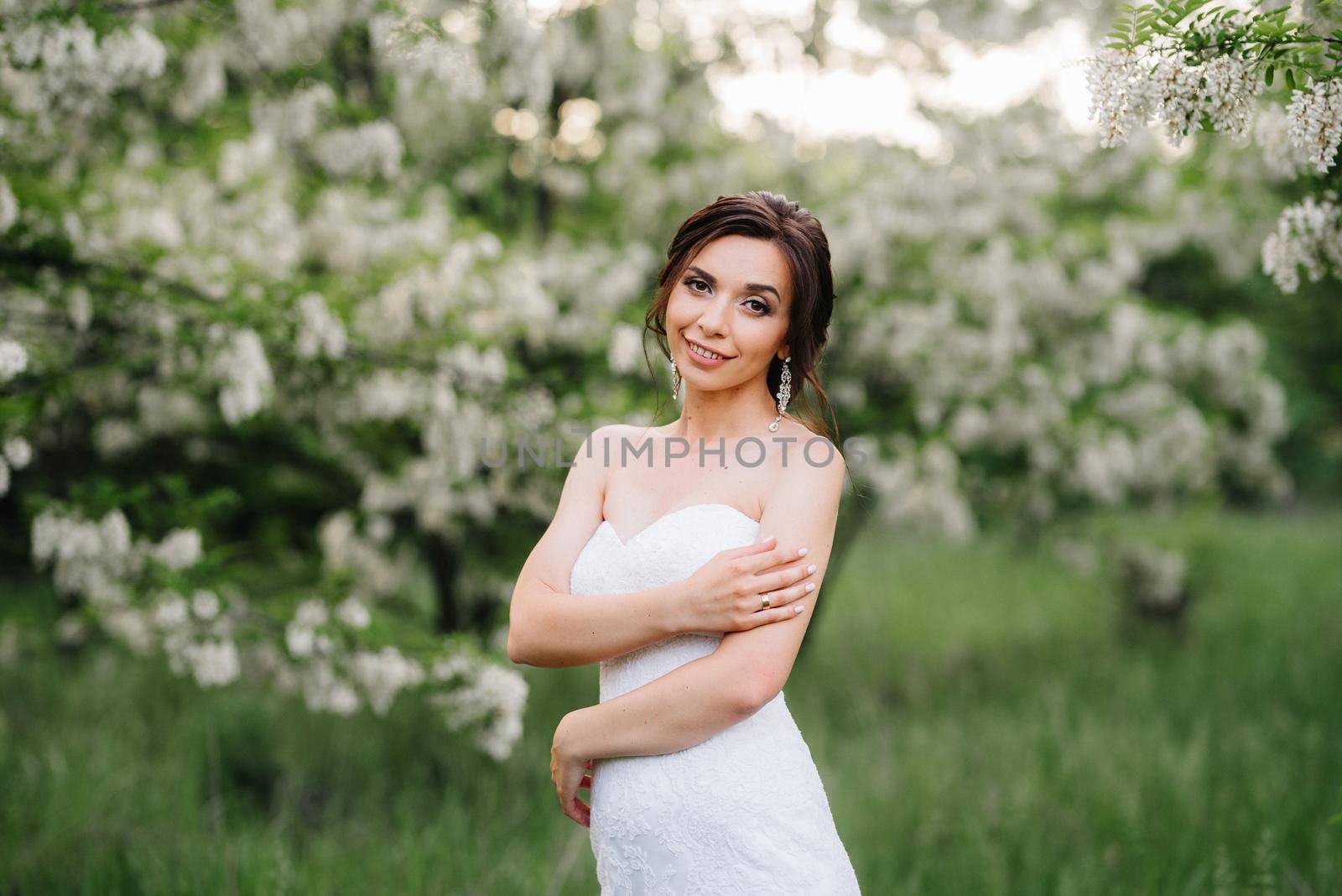 bride in a white dress with a large spring bouquet in a green forest