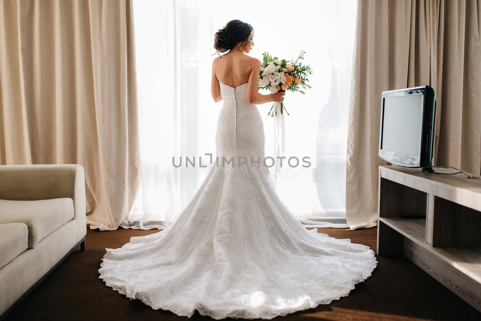 bride in a white dress with a bouquet in a hotel room