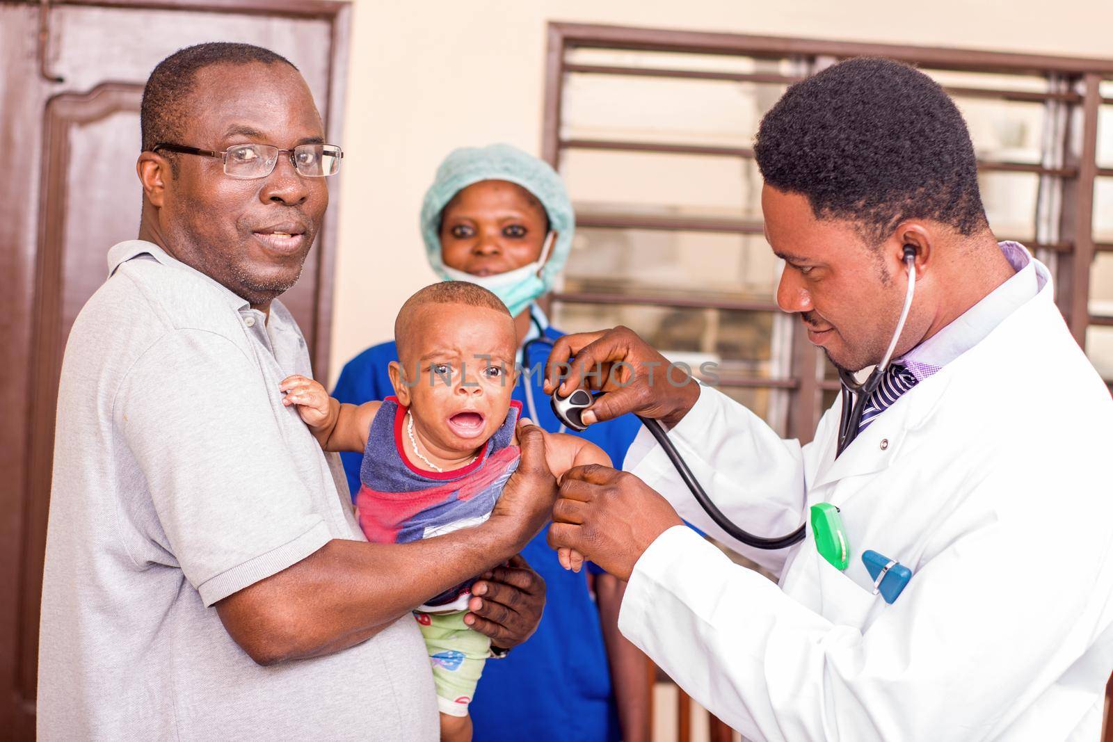 a young man catches his baby during the doctor examines him at the hospital.