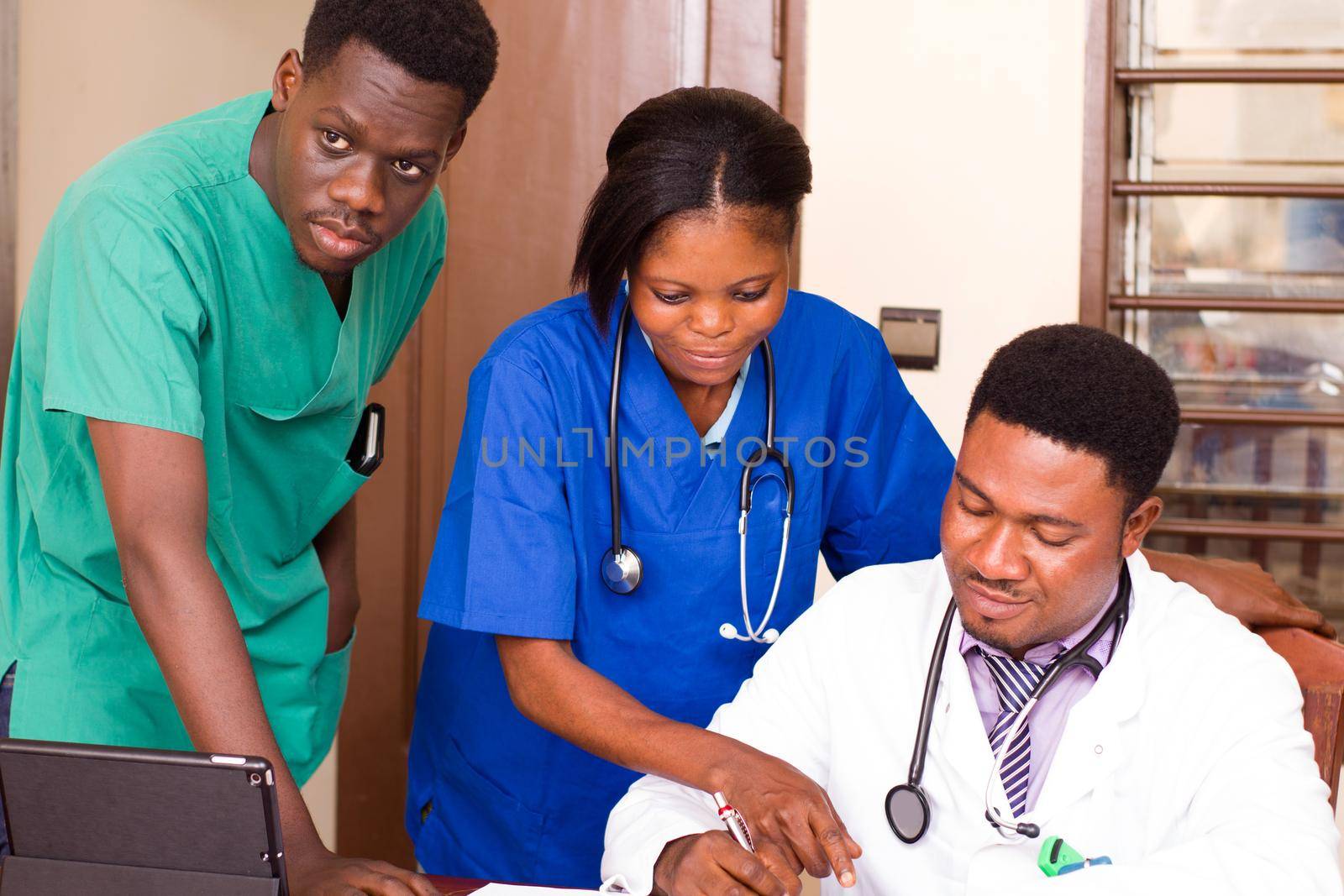 group of mixed doctors with tablet computers meeting at medical office and looking together on the chart of the chief doctor in his office