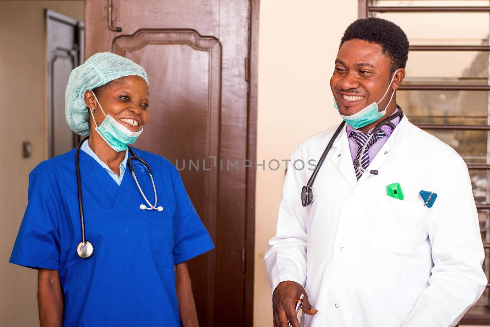 a doctor and his nurse standing in a room laughing.