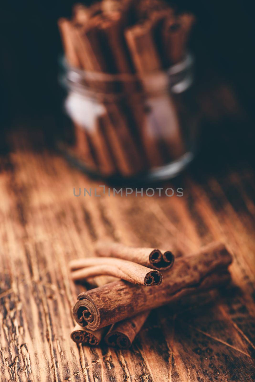 Cinnamon sticks in a glass jar over rustic wooden surface