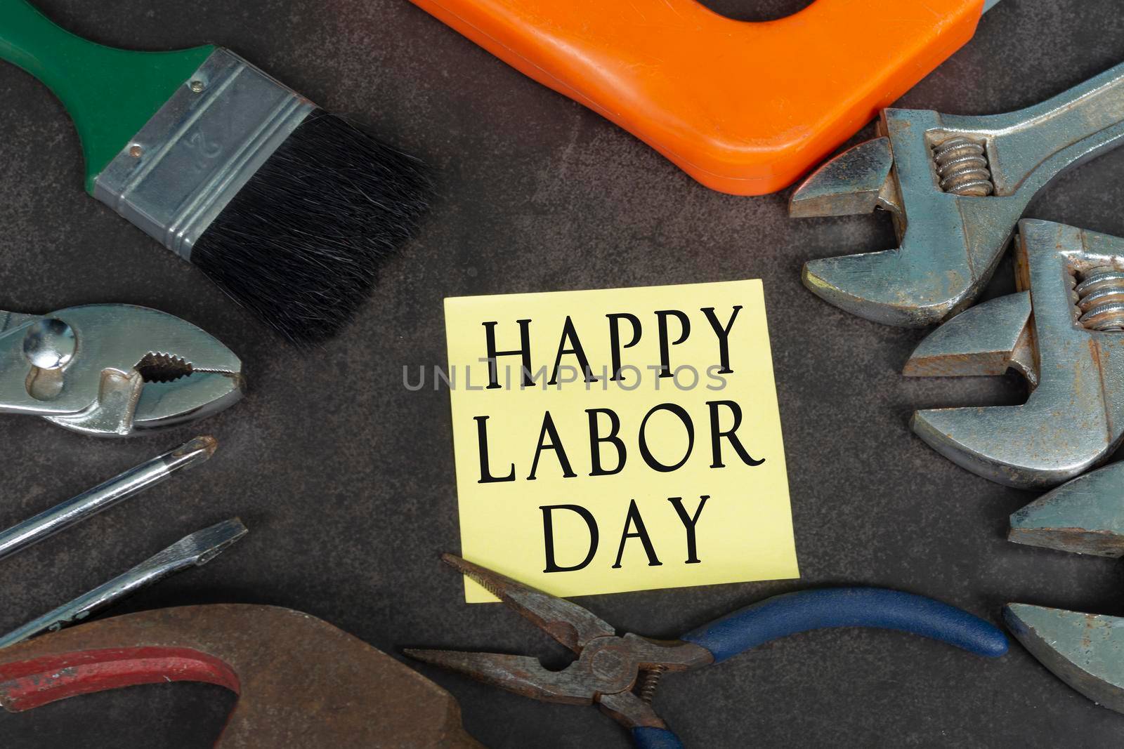 Labor day text on yellow notepad with repair equipment and many handy tools on a dark background