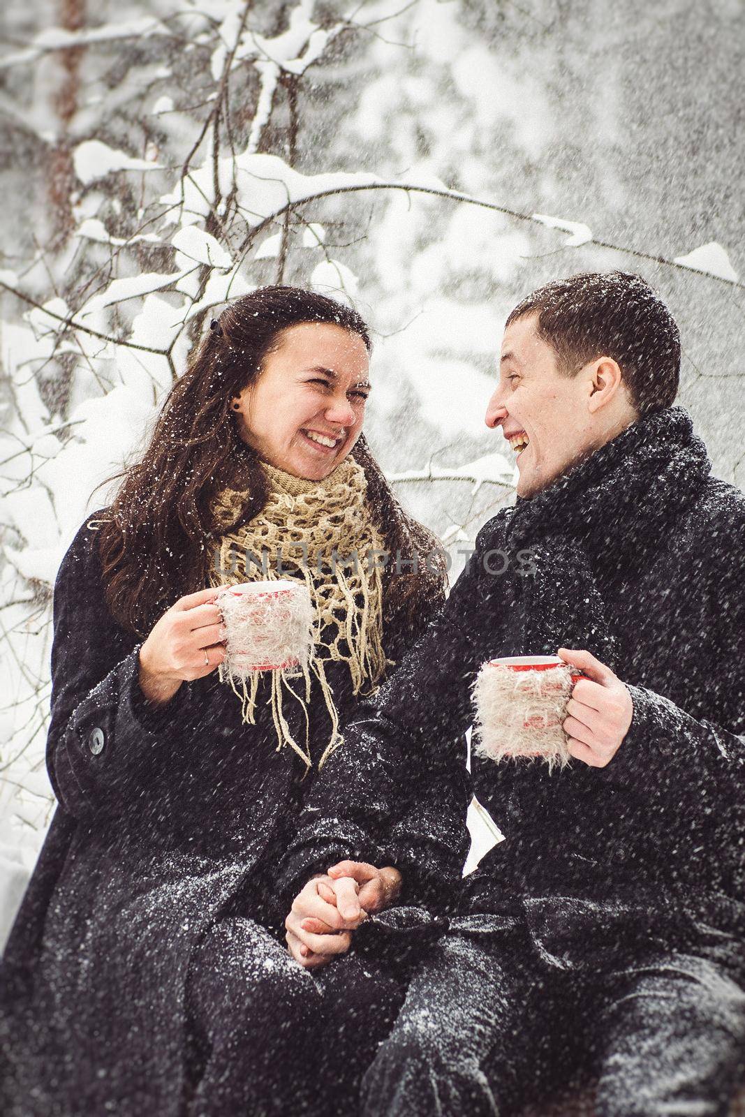 A guy and a girl in warm clothes and scarves on a walk in the snowy forest and in the field