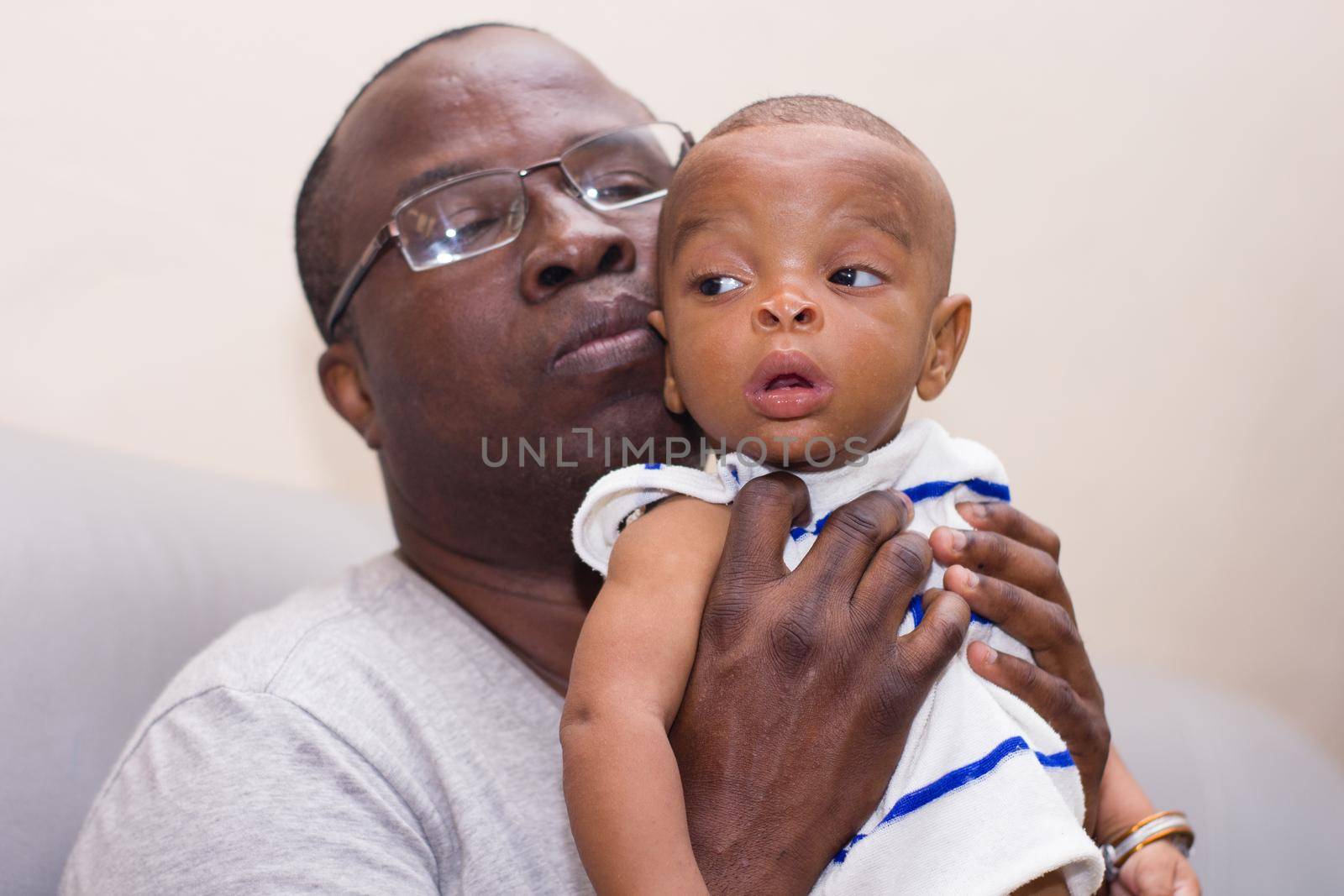 father and baby having fun at home. Proud African father holding an infant in arms while playing.