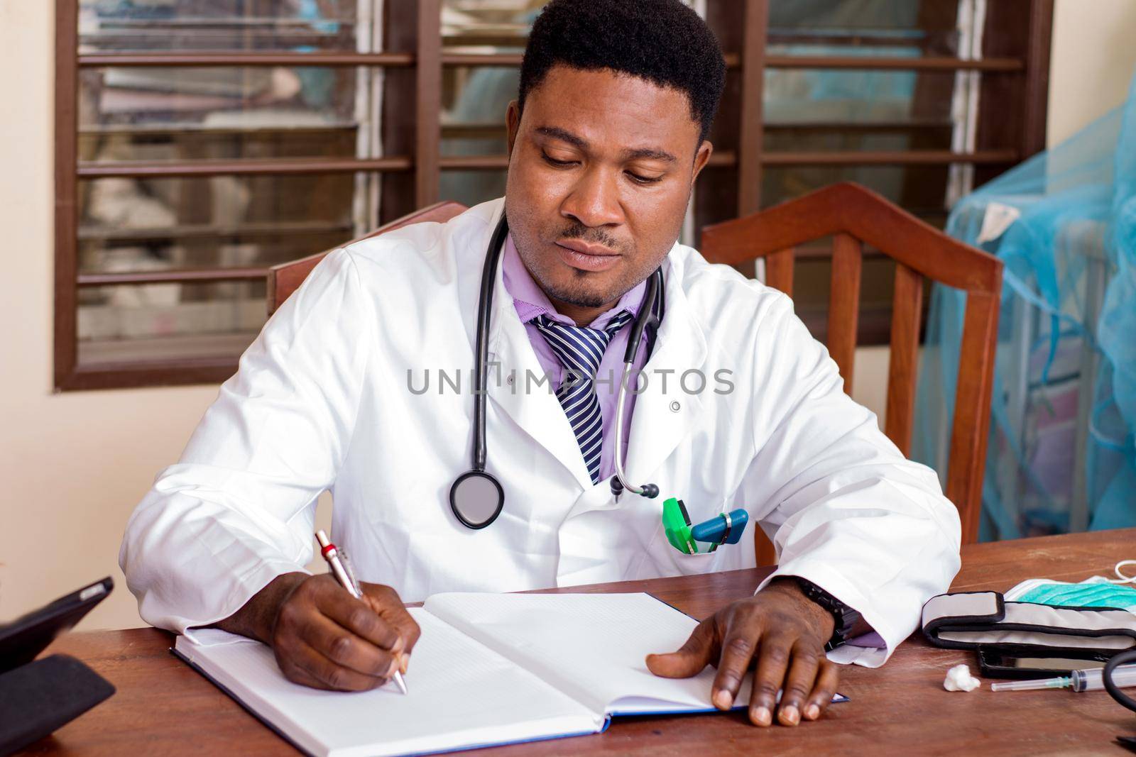 young doctor sitting at desk writing a prescription in a notebook