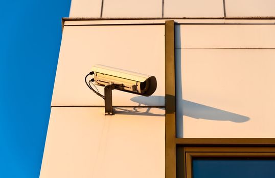 Surveillance cameraon the wall against sky background.