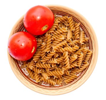 Deep dish with raw wholemeal pasta and fresh tomatoes, isolated on a white background, top view.