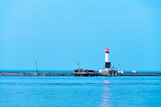 Illuminated lighthouse in twilight, light beam shines in dark skies 