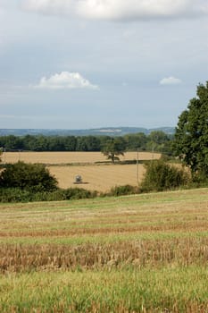 View of English fields with a tractor ploughing in the distance