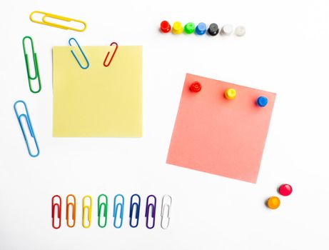 Rainbow paperclips and push pins arranged with sticky notes