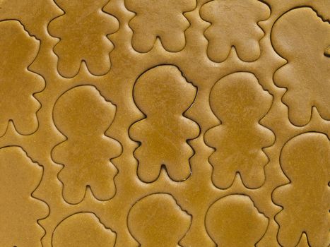 Close-up shot of gingerbread man shapes on gingerbread dough.
