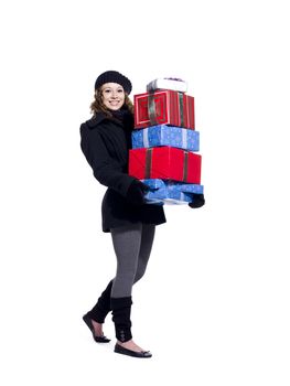 Portrait of a smiling young woman holding a stack of Christmas presents over white background, Model: Brittany Beaudoin