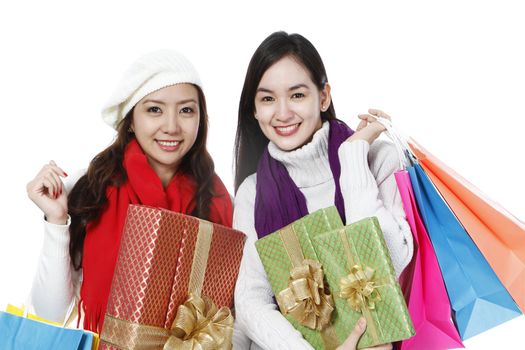 Two young women in winter clothing holding gifts and shopping bags (on white background)