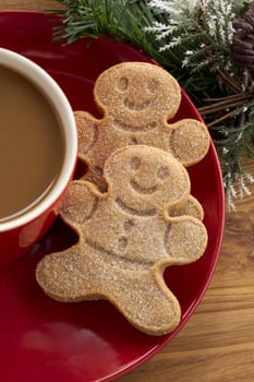 Cropped image gingerbread cookies in red saucer with coffee cup.